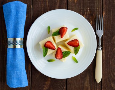 Hassas süzme peynir ve nane yaprakları ve beyaz bir plaka üzerinde taze çilek ile dekorasyon küpler şeklinde kremsi sufle 