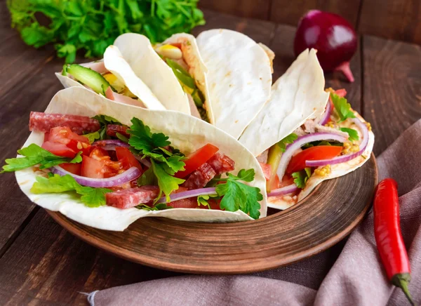 Сэндвичи с зеленью, помидорами, мясом, салями на хрустящем хлебе на столе — стоковое фото