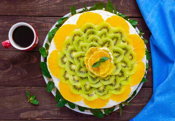 Яскравий круглий святковий фруктовий торт, прикрашений ківі, апельсином, м'ятою і чашкою кави — стокове фото