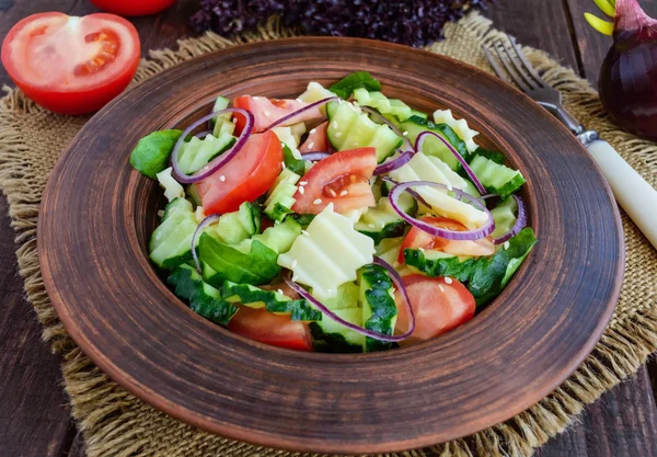 Vitamin saláta uborka, paradicsom, lila hagyma és sajt egy agyag edényben a fából készült asztal — Stock Fotó