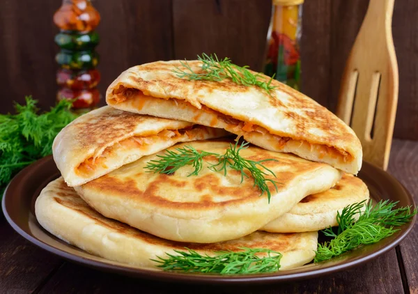 Rustic yeast cakes with cabbage in a clay bow — Stock Photo, Image