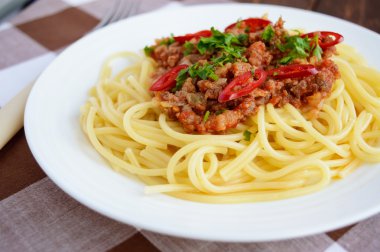 Spagetti Bolognese biber ahşap arka plan üzerinde beyaz bir plaka üzerinde