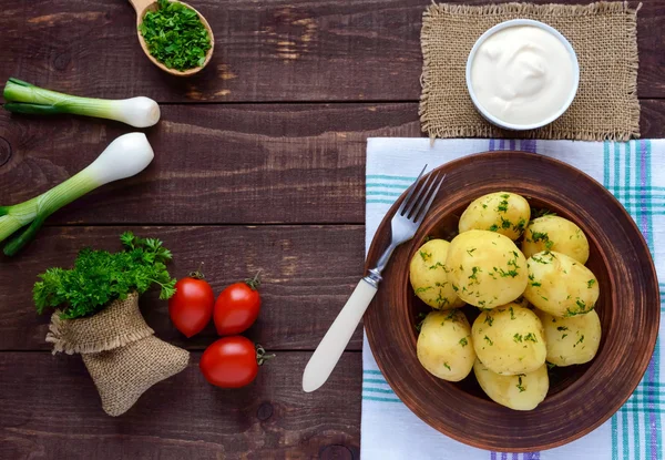 Ung kokt potatis med smör och dill i en lera skål på en trä bakgrund. — Stockfoto