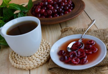 Kiraz reçel ve bir fincan çay ışık ahşap arka plan üzerinde