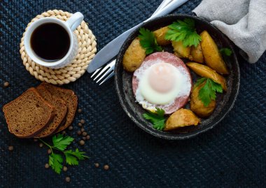 Sahanda yumurta salam ve fırında patates. Bir kızartma tavası sunulması ile bir fincan kahve ve çavdar ekmeği. Kahvaltı.