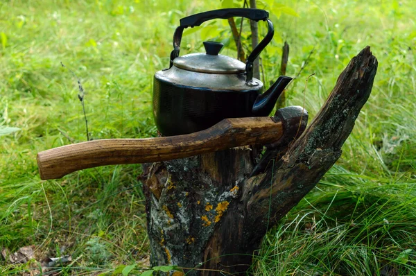 Chaleira vintage para aquecer água e um machado, contra o pano de fundo da natureza. Estilo masculino — Fotografia de Stock