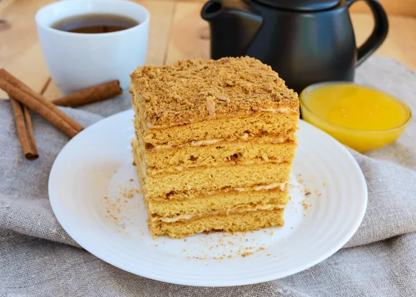 Honey cake and cup of tea on wooden background. Cutting a piece — Stock Photo, Image