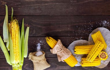 Koyu ahşap arka plan üzerinde pişmiş ve ham corncobs