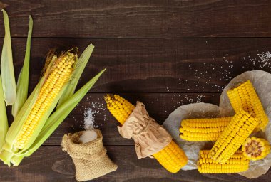 Koyu ahşap arka plan üzerinde pişmiş ve ham corncobs