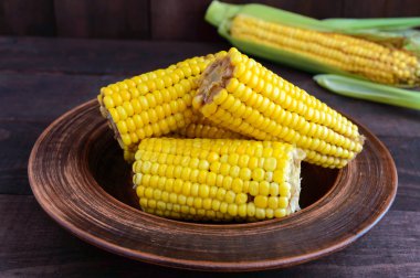 Koyu ahşap arka plan üzerinde pişmiş ve ham corncobs