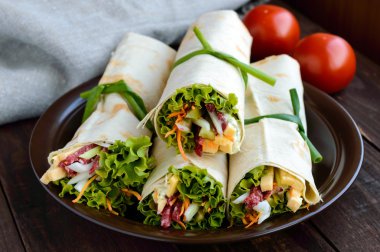Appetizer of pita (lavash) stuffed with: salami, cheese, pickles, carrots,sauce, greens. Shawarma. clipart