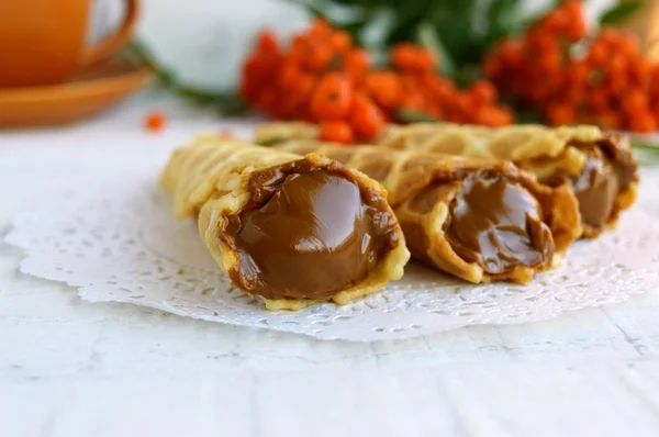 Hemmagjord honung wafers rullade in en kon, fylld med kola (kondenserad mjölk), Rönnbär på en vit bakgrund. — Stockfoto