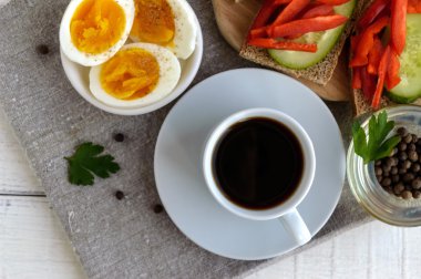 Bir fincan güçlü kahve (espresso), yakın çekim ve kolay diyet kahvaltı - haşlanmış yumurta ve taze sebze (salatalık, kırmızı biber) ile kahverengi ekmek. Üst görünüm.