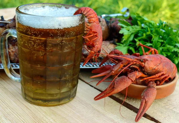 Cerveja espumosa em um copo e crawfish cozido closeup, carne grelhada em espetos no fundo — Fotografia de Stock