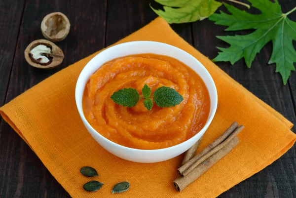 Organic pumpkin puree (soup) in a white bowl on dark wooden background. — Stock Photo, Image
