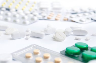 Su toplamış ve beyaz arka plana saçılmış bir sürü hap. Eczane ve sağlık hizmeti teması. Tıbbi geçmiş.