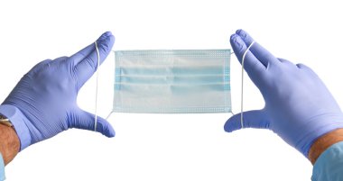 Doktor elleri mavi tıbbi koruyucu yüz maskesi tutuyor. Beyaz bir arka planda izole edilmiş. Sağlık ve kişisel güvenlik kavramı.