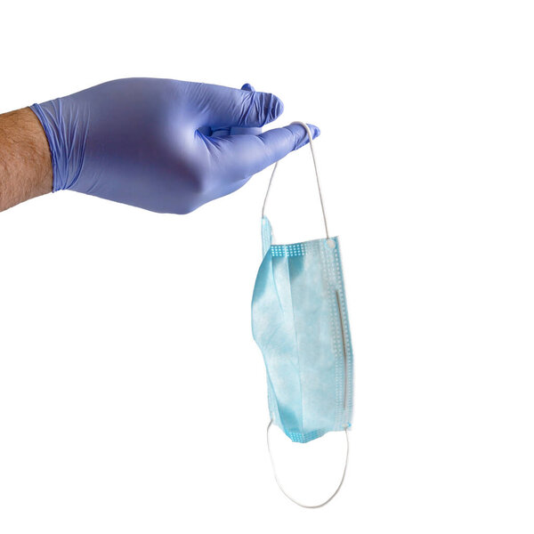 Doctor holds in his hand a protective disposable mask in a blue medical glove on a white background. The concept of the using and recycling of antivirus protective equipment.