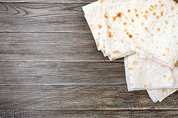 Armenian flat bread lavash. Thin pita bread on wooden background. Top view. Copy space.