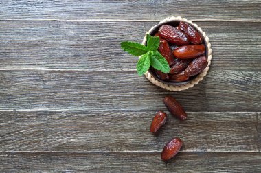 Kurutulmuş meyveler ve taze nane yaprakları ahşap bir masada seramik bir kasede. Organik kurutulmuş meyve. Uzayı kopyala Üst Manzara. Düz yatıyordu