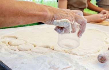 Kadın hamurdan daireler kesiyor. Aşçı çocuklara tatlı çörek yapmayı öğretiyor. Pişirmede yüksek lisans. Evde yemek pişirmek..