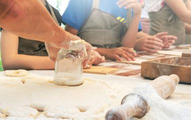 Kadın hamurdan daireler kesiyor. Aşçı çocuklara tatlı çörek yapmayı öğretiyor. Pişirmede yüksek lisans. Evde yemek pişirmek..