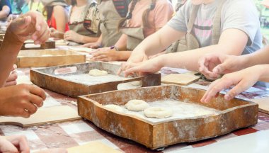 Çocuklar hamurdan çörek yapar ve onları ahşap tepsilere koyar. Pişirmede yüksek lisans dersi.