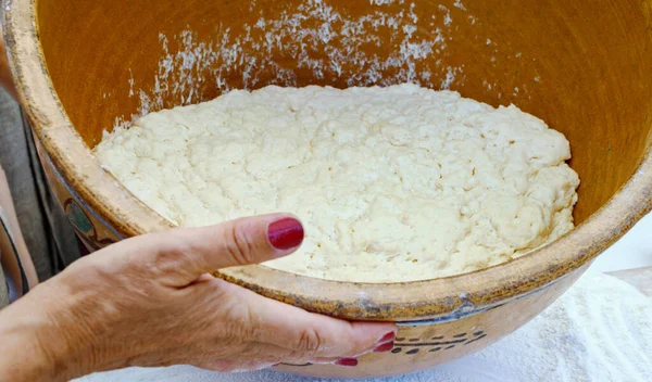 一个女人拿着一个大的正宗的粘土碗 里面有酵母面团 在家里做饭 制作甜甜甜圈的硕士课程 — 图库照片