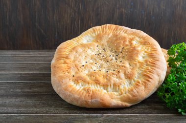 Geleneksel Asya sade ekmeği. Ahşap bir arka planda susam tohumlu taze pişmiş ekmek..