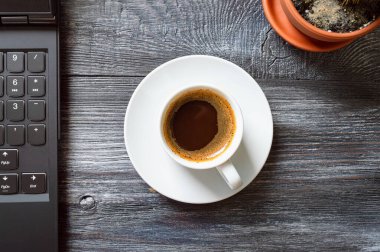 Bir fincan kahve, dizüstü bilgisayar, tahta bir masada kaktüs, üst manzara, düz yatak. Evdeki işyerinde. Çevrimiçi Eğitim.