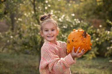 Çocuk ellerinde deforme olmuş çirkin turuncu balkabağı.