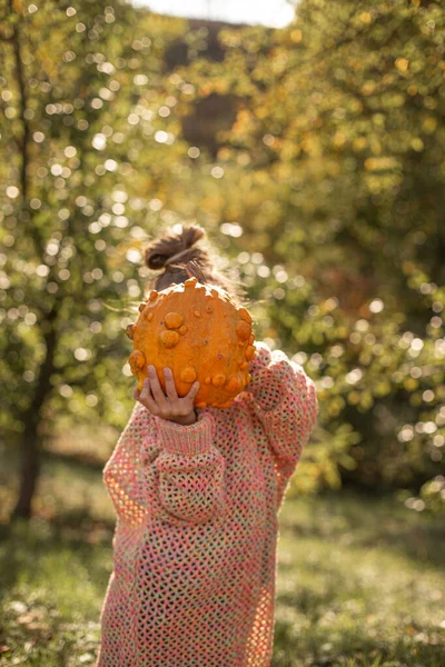 Deformed ugly orange pumpkin in a child hands.