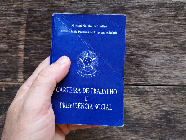Hand holding Brazilian document work and social security with wooden background