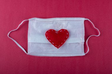 Kırmızı kalpler beyaz Covid maskesi üzerinde.