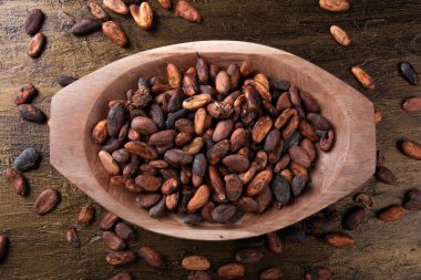 Ahşap tepsinin içinde çiğ kakao çekirdekleri ve kırsal arka plan manzarası..