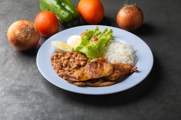 Brazilian food dish with rice beans and chicken.