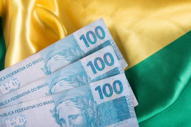 Brezilya bayrağı üzerine 100 reais not.
