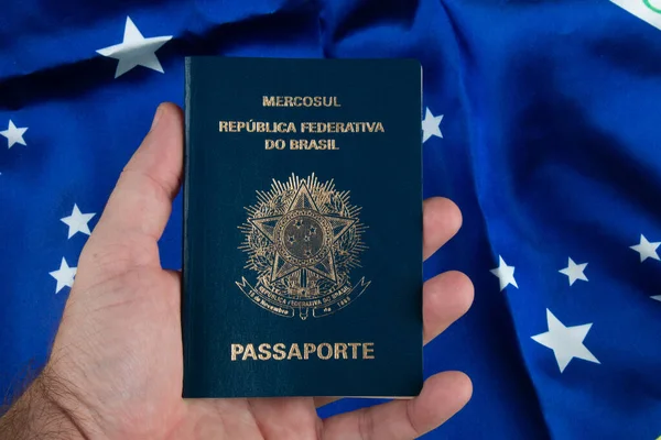 Mão Segurando Passaporte Brasileiro Com Bandeira Brasileira Segundo Plano — Fotografia de Stock