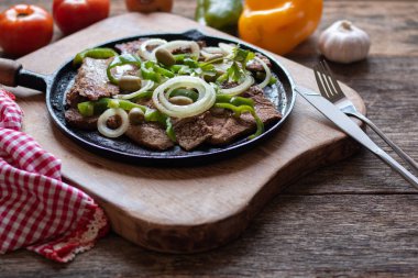 Kırsal ahşap kaplamalı demir tabakta kızarmış et..