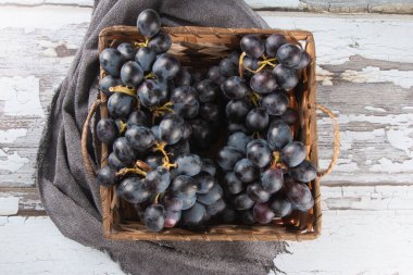 Eski ahşap arka planda sepetteki mor meyve üzümü.