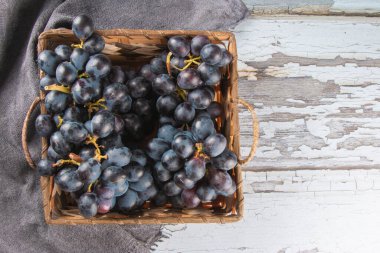 Eski ahşap arka planda sepetteki mor meyve üzümü.