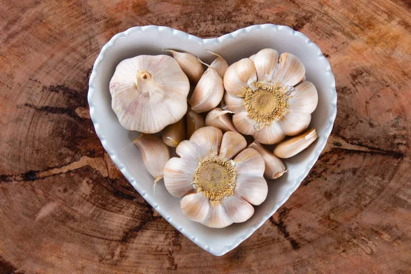 stock image Garlic Cloves and Bulb in Heart Bowl with Wood Background.