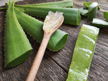 Aloe Vera yaprakları dilimler ve ahşap kaşık üzerinde jöle ile ahşap kırsal arka planda.