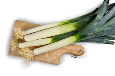 Tahta kesme tahtasındaki pırasalar ve beyaz bir arka plan.