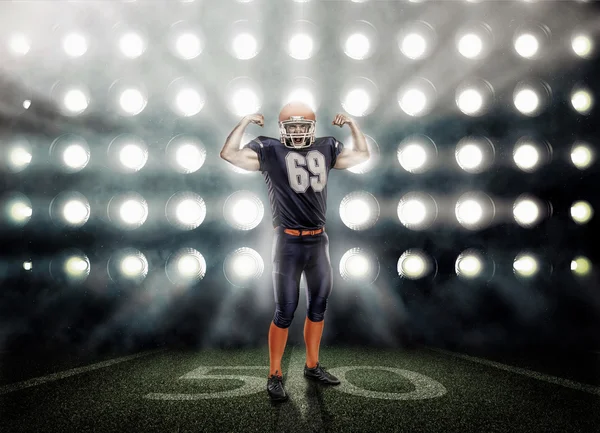 Mavi üniforma tarafından projektörler aydınlatılmış gurur Amerikan futbolu oyuncusu — Stok fotoğraf