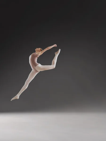 Krásné baleríny pózuje v skok na šedém pozadí — Stock fotografie