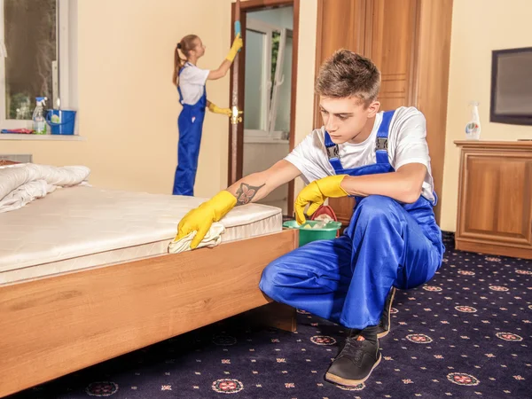 Уборщицы чистят мебель и пол в комнате — стоковое фото