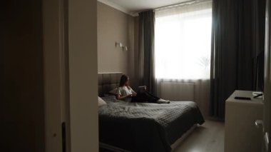 Relaxing afternoon in a cozy bedroom with a young woman reading quietly