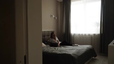 Relaxing afternoon in a cozy bedroom with a person using a laptop on the bed