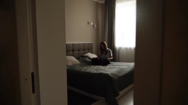 Woman sitting on bed with cat in a cozy bedroom during the day